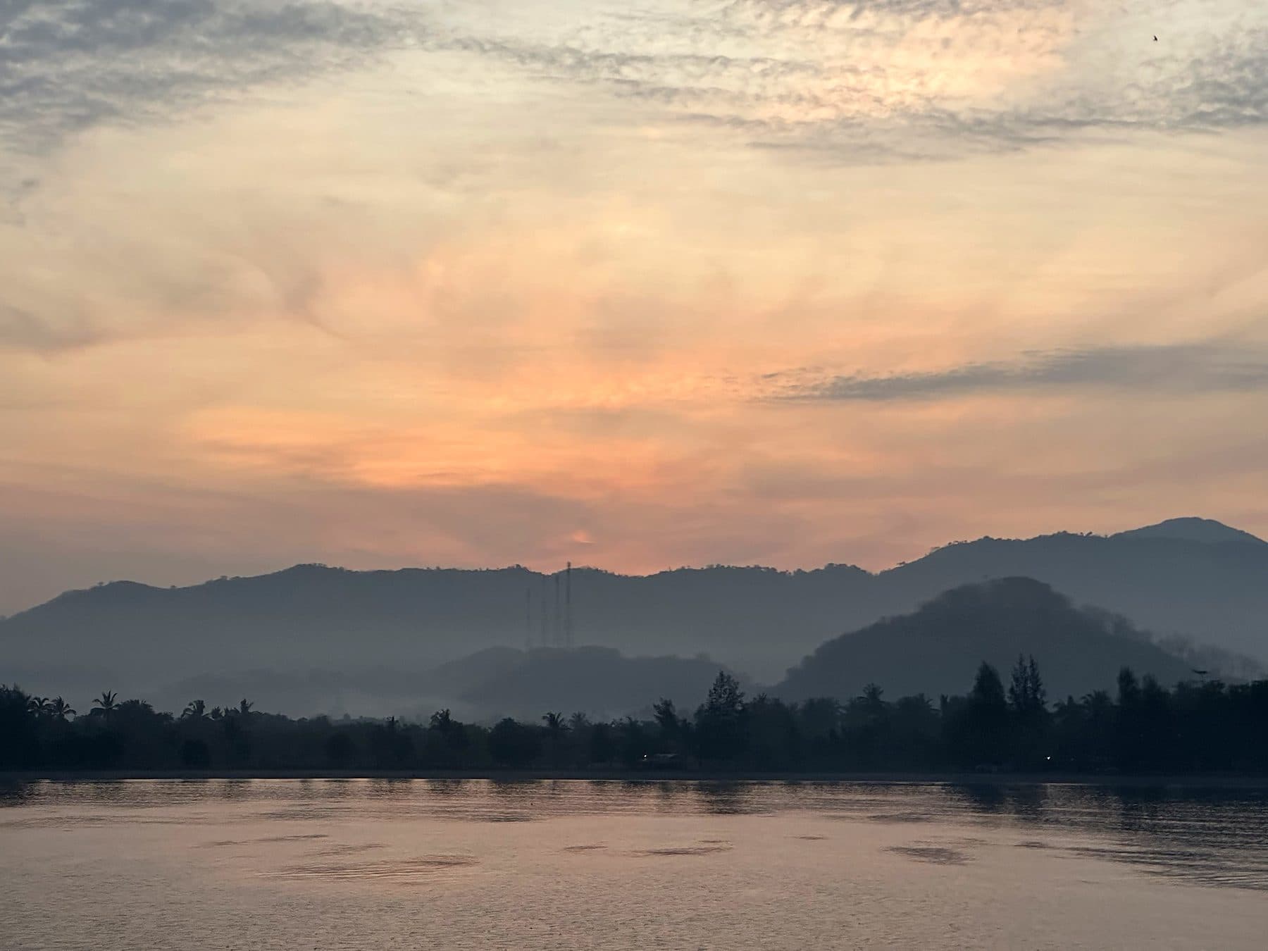 Sunrise over misty hills and calm water